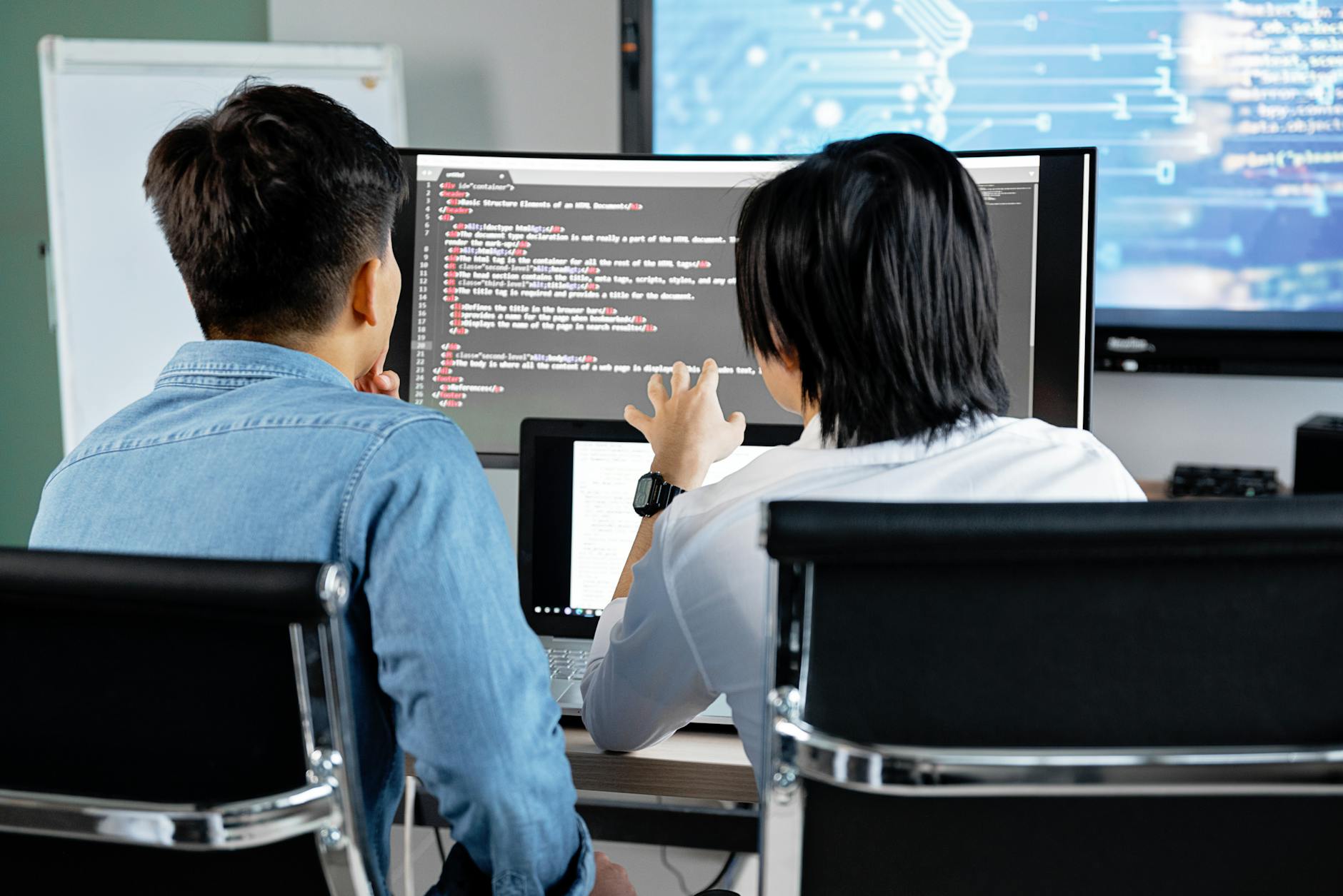 Dwóch programistów omawia kod na monitorze w biurze