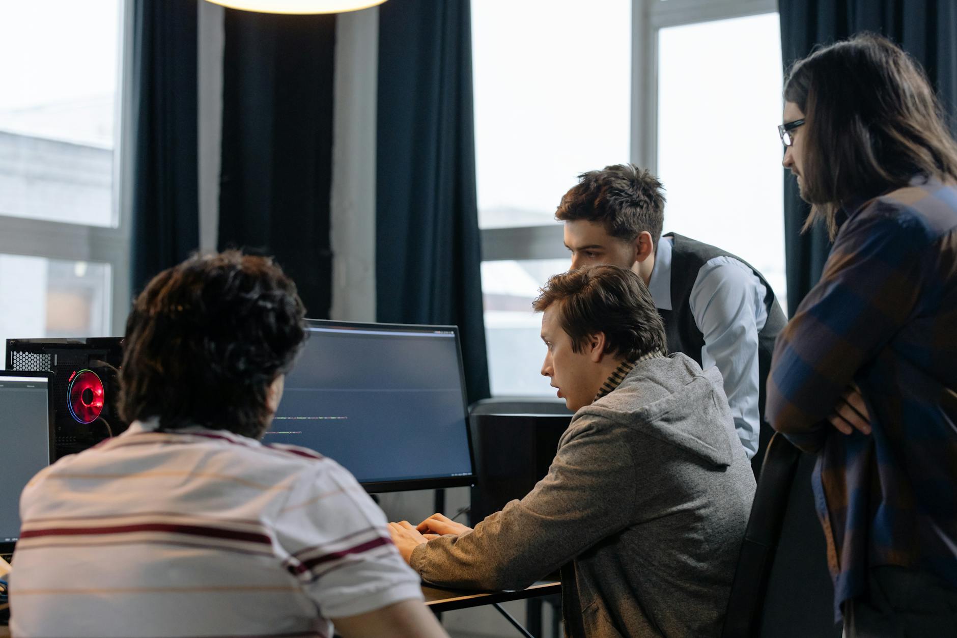 Zespół programistów przy komputerach omawia projekt oprogramowania