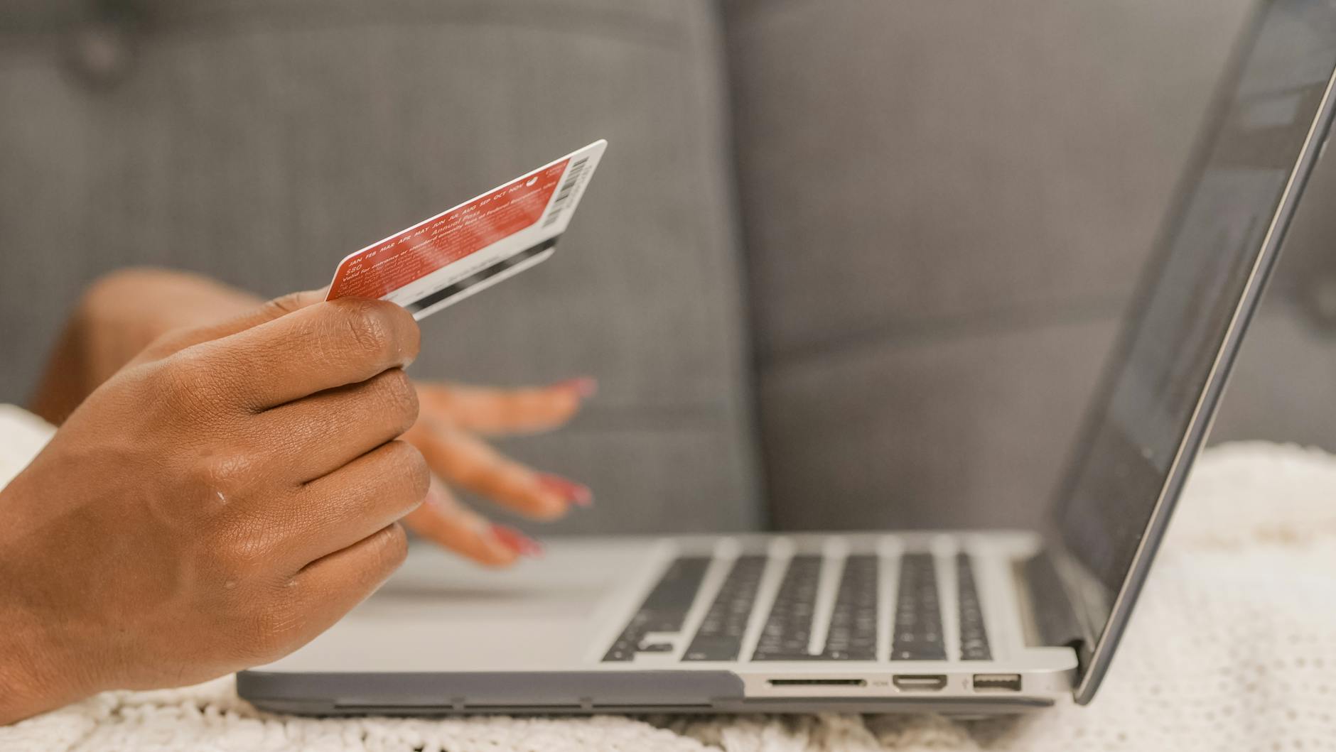 Dłoń płacąca kartą kredytową za zakupy online na laptopie