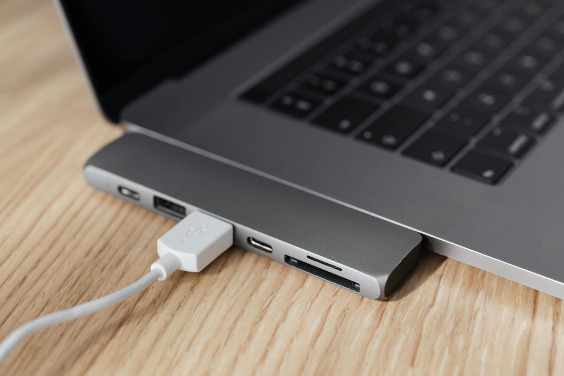 Laptop z podłączoną stacją dokującą USB C na drewnianym biurku