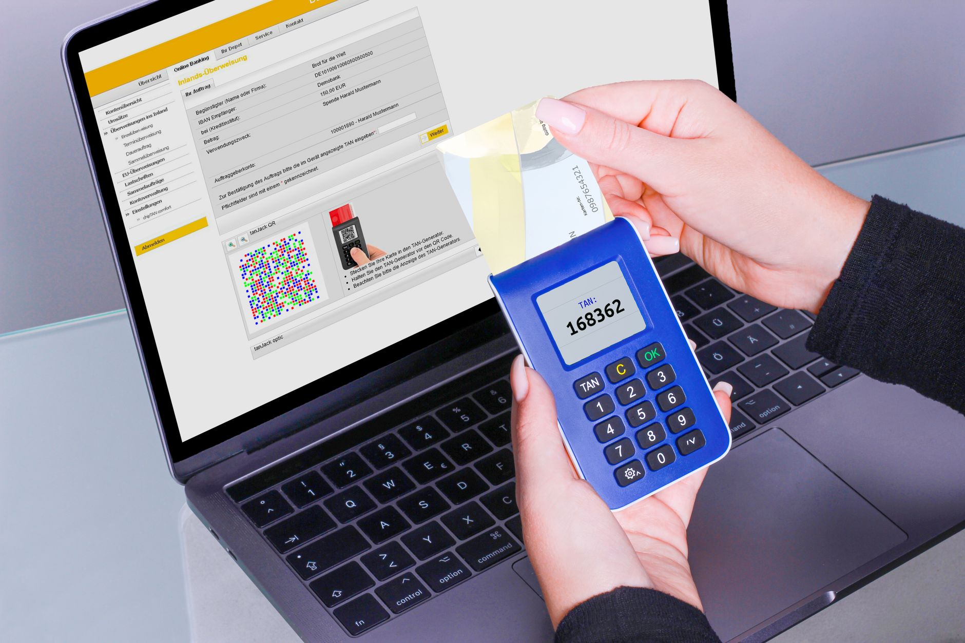 Dłonie korzystające z czytnika TAN obok laptopa podczas bankowości online