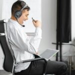 Mężczyzna w słuchawkach z ANC podczas wideokonferencji na laptopie