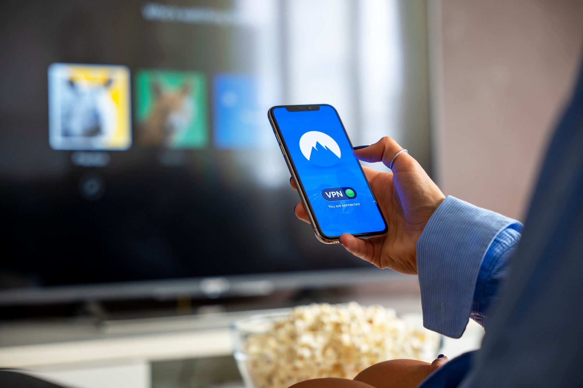 Osoba w domu korzysta z VPN na smartfonie, oglądając treści na smart TV