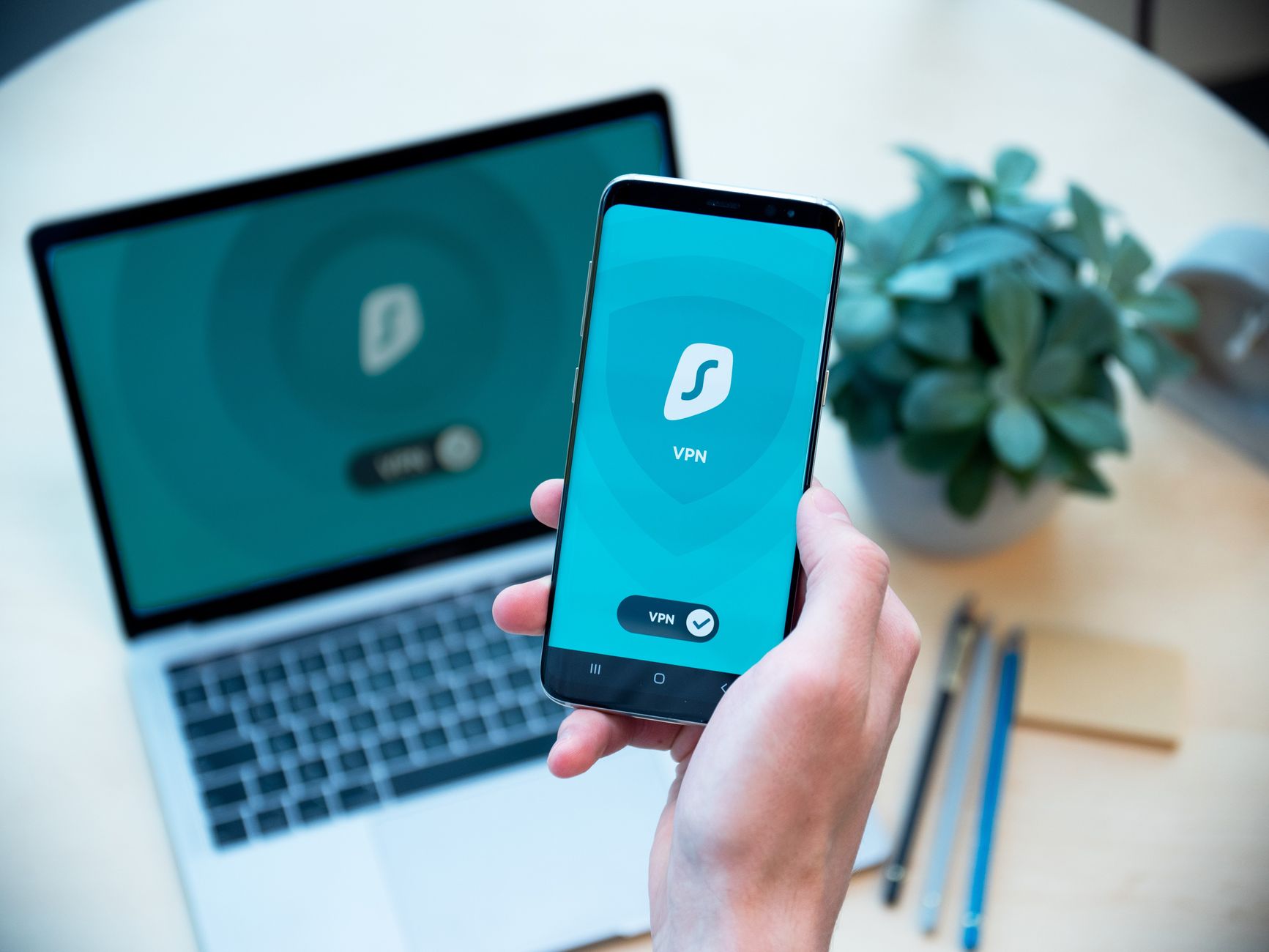 Smartfon z włączoną aplikacją VPN na tle laptopa, symbol bezpieczeństwa Smartfon z włączoną aplikacją VPN na tle laptopa, symbol bezpieczeństwa